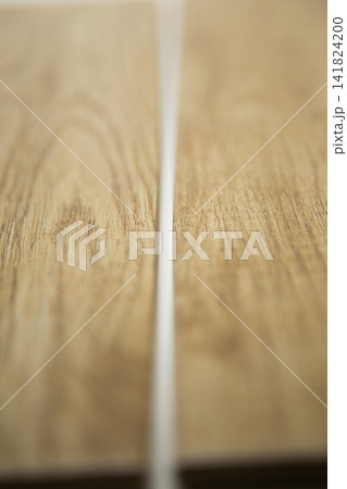 Vertical close-up photo of wood-colored porcelain stoneware tiles lying apart with a white vertical joint in between, showing the tiling and grouting. The concept of choosing and laying tiles, repairs Vertical close-up photo of wood-colored porcelain stoneware tiles lying apart with a white vertical joint in between, showing the tiling and grouting. The concept of choosing and laying tiles, repairs 141824200