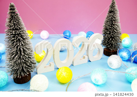 Happy New Year 2026 with mini Christmas tree and LED cotton balls decoration on pink blue background Happy New Year 2026 with mini Christmas tree and LED cotton balls decoration on pink blue background 141824430