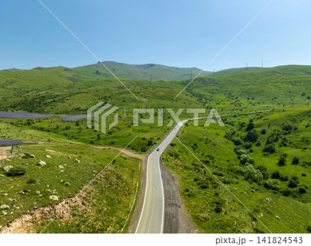 Aerial view of a rural road winding through green hills with solar panels Aerial view of a rural road winding through green hills with solar panels 141824543