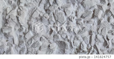 Close up of a rough, light gray concrete wall embedded with small pebbles and stones 141824757