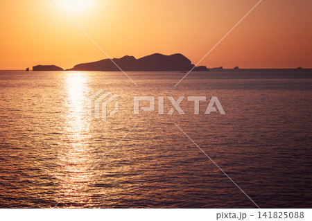Sa Conillera off Platges de Comte, dark island silhouette under orange and purple sky. Sa Conillera off Platges de Comte, dark island silhouette under orange and purple sky. 141825088