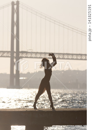 Dance performance by the water near a bridge at sunset on a warm evening Dance performance by the water near a bridge at sunset on a warm evening 141825191