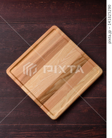 A square wooden cutting board for home food preparation. A wooden cutting board A square wooden cutting board for home food preparation. A wooden cutting board 141825290
