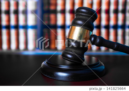 Wooden judge gavel with sound block in front of colorful law books on shelf, court justice and legal system concept Wooden judge gavel with sound block in front of colorful law books on shelf, court justice and legal system concept 141825664