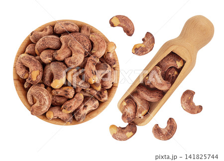 cashew nuts with shell in wooden bowl and scoop isolated on white background. Top view. Flat lay cashew nuts with shell in wooden bowl and scoop isolated on white background. Top view. Flat lay 141825744