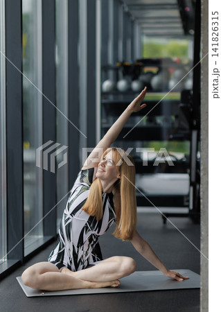 Woman stretching in yoga pose on mat in gym Woman stretching in yoga pose on mat in gym 141826315
