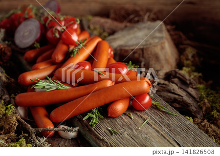 Smoked sausages with tomatoes, onion, garlic, and rosemary on an old board. Smoked sausages with tomatoes, onion, garlic, and rosemary on an old board. 141826508