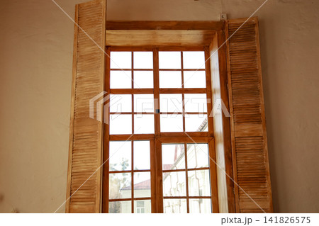Window with wooden shutters in a bright room showing sunlight on a clear day Window with wooden shutters in a bright room showing sunlight on a clear day 141826575