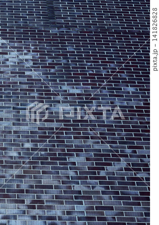 The view shows a roof made of dark bricks taken from above in a residential neighborhood under clear blue sky at midday 141826828