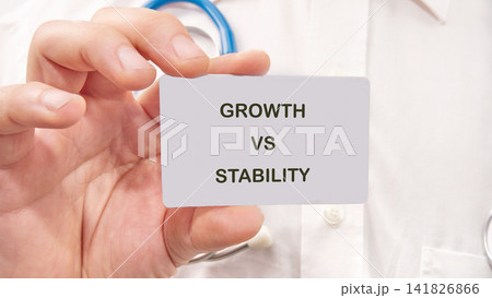 A person holds up a card that reads growth versus stability. The setting appears to be a healthcare environment. The focus is on exploring different approaches and outcomes A person holds up a card that reads growth versus stability. The setting appears to be a healthcare environment. The focus is on exploring different approaches and outcomes 141826866