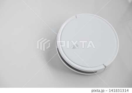 White automatic floor cleaner with side brush on tile flooring, designed for efficient cleaning. Robot vacuum concept of smart home technology for seamless, wireless cleaning White automatic floor cleaner with side brush on tile flooring, designed for efficient cleaning. Robot vacuum concept of smart home technology for seamless, wireless cleaning 141831314