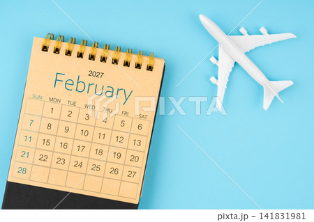 February 2027 calendar and airplane toy on blue background. February 2027 calendar and airplane toy on blue background. 141831981
