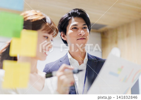 会議室で透明ボードを使って打合せするビジネスマン 141832846