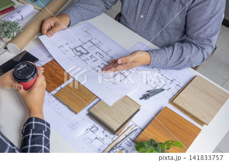 Interior designer reviewing apartment layout blueprint and materials at desk. Interior designer reviewing apartment layout blueprint and materials at desk. 141833757