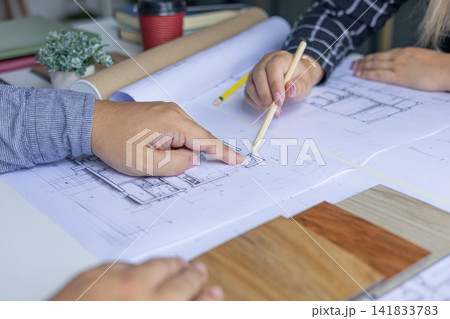 Architect and Interior Designer Collaborating on Floor Plans with Wood Samples. 141833783