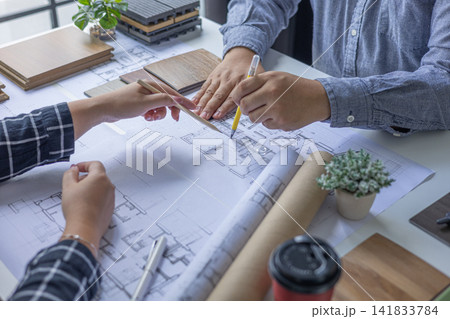 Architects and interior teamwork cooperate on plan project design and choosing material for home interior, drawing on blueprint. 141833784