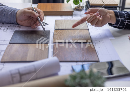 Architect and Interior Designer Collaborating on Floor Plans with Wood Samples. Architect and Interior Designer Collaborating on Floor Plans with Wood Samples. 141833791