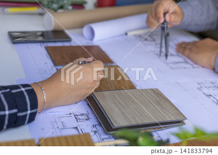 Interior design teamwork cooperates on selecting variety of wood-textured samples for flooring or furniture materials. 141833794