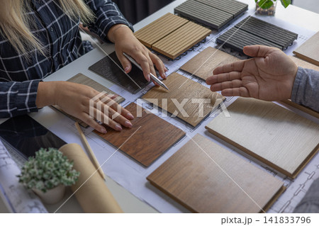 Interior design teamwork cooperates on selecting variety of wood-textured samples for flooring or furniture materials. Interior design teamwork cooperates on selecting variety of wood-textured samples for flooring or furniture materials. 141833796