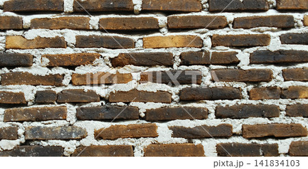 Rustic brown clay brick wall with thick white mortar joints. 141834103
