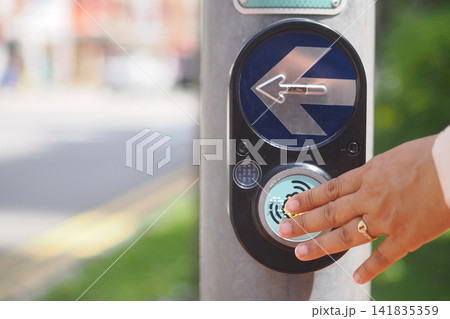 Requesting to cross at a pedestrian signal in the city Requesting to cross at a pedestrian signal in the city 141835359