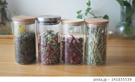 Glass jars with herbs and flowers on a wooden table Glass jars with herbs and flowers on a wooden table 141835539