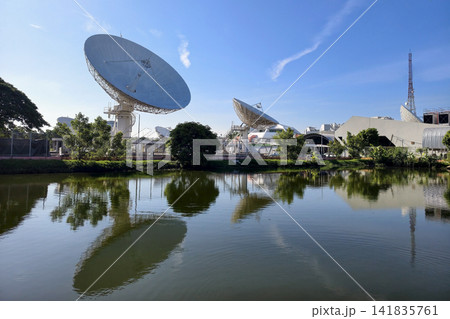 Satellite dish antenna stations with skyline reflection on pond Satellite dish antenna stations with skyline reflection on pond 141835761