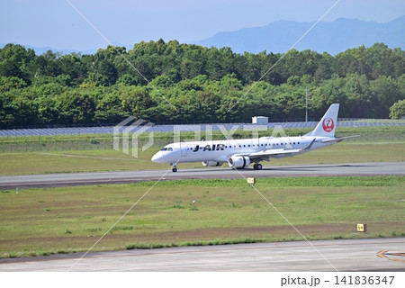 緑鮮やかな風景を背景に滑走するJ-AIR機 141836347