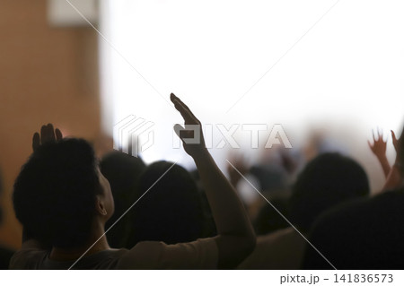 A holy worshipper raising both hands before the presence of the Holy Spirit to worship, praise, and pray to God, background of gatherings and retreats 141836573