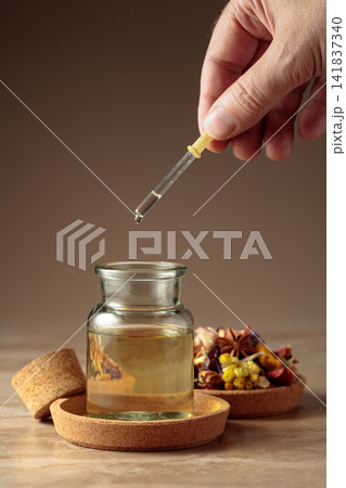 Dropping essential oil or herbal tincture into a glass bottle. 141837340