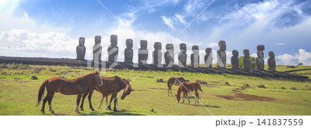 Wild horses grazing near ancient moai statues of Ahu Tongariki in Easter Island, panorama with copy space Wild horses grazing near ancient moai statues of Ahu Tongariki in Easter Island, panorama with copy space 141837559