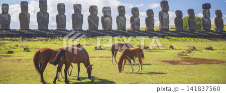 Horses on pasture in front of stone moai statues of Ahu Tongariki in Easter Island, panorama with copy space Horses on pasture in front of stone moai statues of Ahu Tongariki in Easter Island, panorama with copy space 141837560