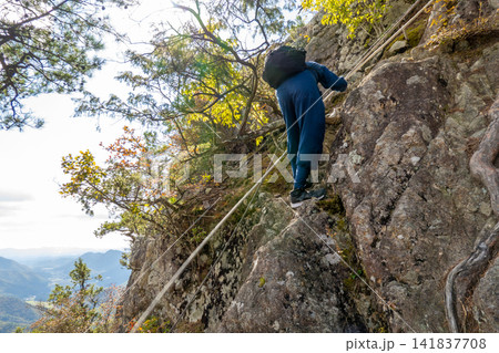 兵庫県丹波篠山市の白髪岳で、険しいロープ場の岩肌を慎重に登る登山者の後ろ姿※作品コメント欄に撮影位置 兵庫県丹波篠山市の白髪岳で、険しいロープ場の岩肌を慎重に登る登山者の後ろ姿※作品コメント欄に撮影位置 141837708