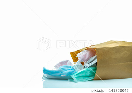Used surgical face mask in brown paper bag isolated on white background. Medical waste. Infectious waste from coronavirus crisis. Used medical face mask waiting for disposal with hygienic process. Used surgical face mask in brown paper bag isolated on white background. Medical waste. Infectious waste from coronavirus crisis. Used medical face mask waiting for disposal with hygienic process. 141838045