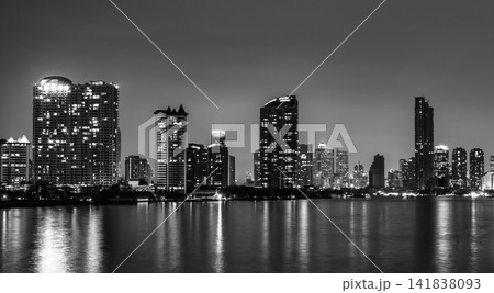 Black and white Bangkok skyline at night along Chao Phraya River in Thailand. Illuminated skyscrapers, waterfront reflections and timeless monochrome urban architecture. Night cityscape in Thailand. Black and white Bangkok skyline at night along Chao Phraya River in Thailand. Illuminated skyscrapers, waterfront reflections and timeless monochrome urban architecture. Night cityscape in Thailand. 141838093