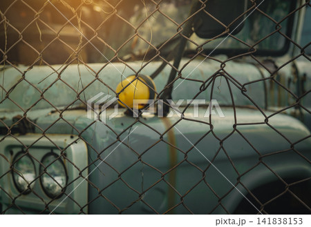 Abandoned rusty truck behind wire fence in industrial scrapyard. Vehicle decay, weathered metal, economic recession, financial loss, urban abandonment and transportation failure. financial recession. 141838153