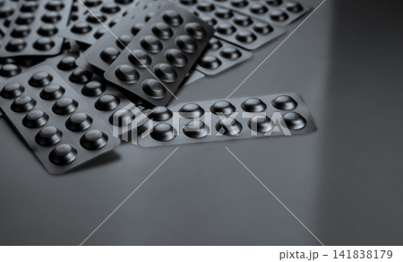 Silver aluminum blister packs with copy space on gray background for pharmaceutical industry. Hospital medicine supplies, pharmacy products, prescription drug packaging and healthcare retail market. Silver aluminum blister packs with copy space on gray background for pharmaceutical industry. Hospital medicine supplies, pharmacy products, prescription drug packaging and healthcare retail market. 141838179
