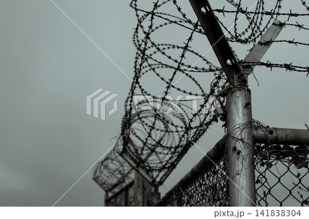 Prison security fence. Barbed wire security fence. Razor wire jail fence. Barrier border. Boundary security wall. Prison for arrest criminals or terrorists. Private area. Military zone concept. Prison security fence. Barbed wire security fence. Razor wire jail fence. Barrier border. Boundary security wall. Prison for arrest criminals or terrorists. Private area. Military zone concept. 141838304