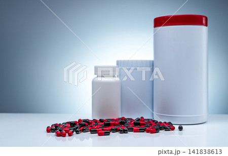 Antibiotic capsule pills spread on white table and plastic drug bottle white blank label. Antibiotic drug resistance. Pharmaceutical manufacturing production. Pharmaceutical industry. Pharmacy 141838613