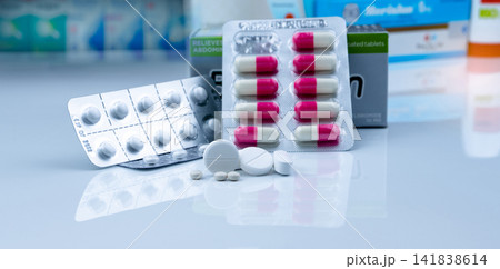 Pills in pharmacy shop. White tablets pills on blurred capsule in blister pack and white tablets pills in pack near drug box package. Pharmacy products. Pharmaceutical industry. Drugstore business. 141838614