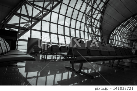 Empty seat in departure lounge at airport terminal. Social distancing for safety. Coronavirus crisis impact on aviation business. No passenger in the airport. Priority seating. Black and white scene. 141838721