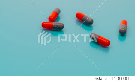 Gray-orange antibiotic capsules pill spread on blue background. Pharmacy banner. Prescription drug. Antibiotic drug resistance. Pharmaceutical industry. Healthcare and medicine. Antimicrobial drugs. Gray-orange antibiotic capsules pill spread on blue background. Pharmacy banner. Prescription drug. Antibiotic drug resistance. Pharmaceutical industry. Healthcare and medicine. Antimicrobial drugs. 141838816
