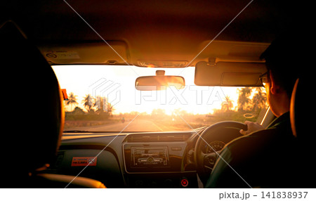 Driving along an open countryside road during golden hour viewed from inside a modern vehicle, capturing a peaceful travel experience, transportation lifestyle and freedom of road trip adventure. 141838937