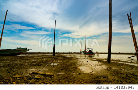 Landscape of sea at tide and blue sky and clouds with fisherman's boat. Sea mud beach when the water lower. Fishing boat parked at the shore. Lifestyle and culture of local fishermen in Thailand. 141838945
