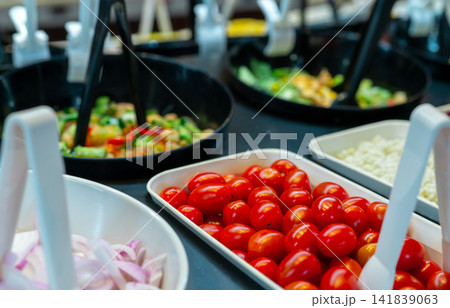Salad bar buffet at restaurant. Fresh salad bar buffet for lunch or dinner. Healthy food. Selective focus on red tomatoes in white bowl on counter. Catering food. Banquet service. Vegetarian food. 141839063