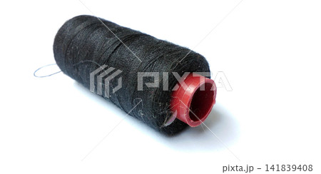 Spool of black cotton sewing thread with a red bobbin 141839408