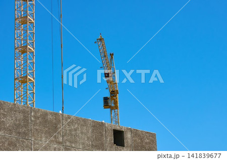 Construction crane stands tall against a clear blue sky during daylight in an urban area Construction crane stands tall against a clear blue sky during daylight in an urban area 141839677