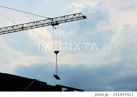 Silhouette of Industrial Tower Crane Lifting Slab against Cloudy Sky 141841421