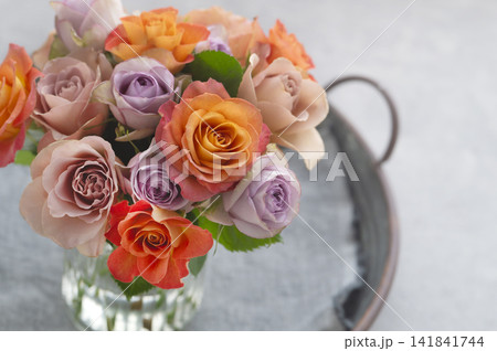ガラス花瓶に活けられたオレンジやパープルの色鮮やかなバラの花束 141841744