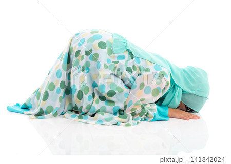 Side view horizontal portrait of cute young Asian Muslim girl performing Sujud prostration isolated on white background. Side view horizontal portrait of cute young Asian Muslim girl performing Sujud prostration isolated on white background. 141842024